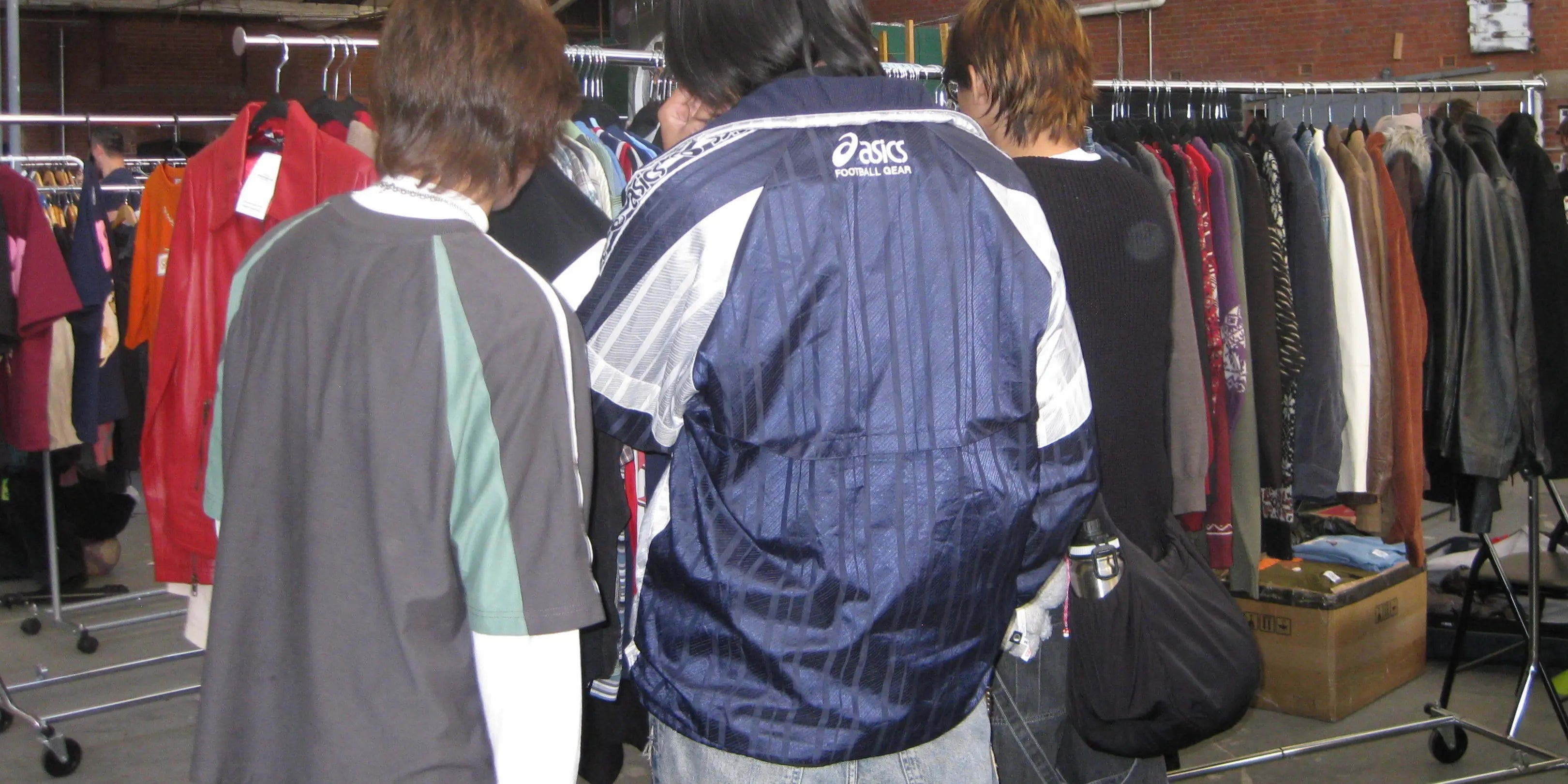 Customers wearing a vintage bomber jacket looking through clothing racks
