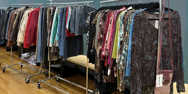 Rack of vintage long sleeve tops in front of some other racks of vintage clothes